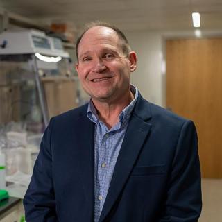 Rick poses for a headshot in a lab