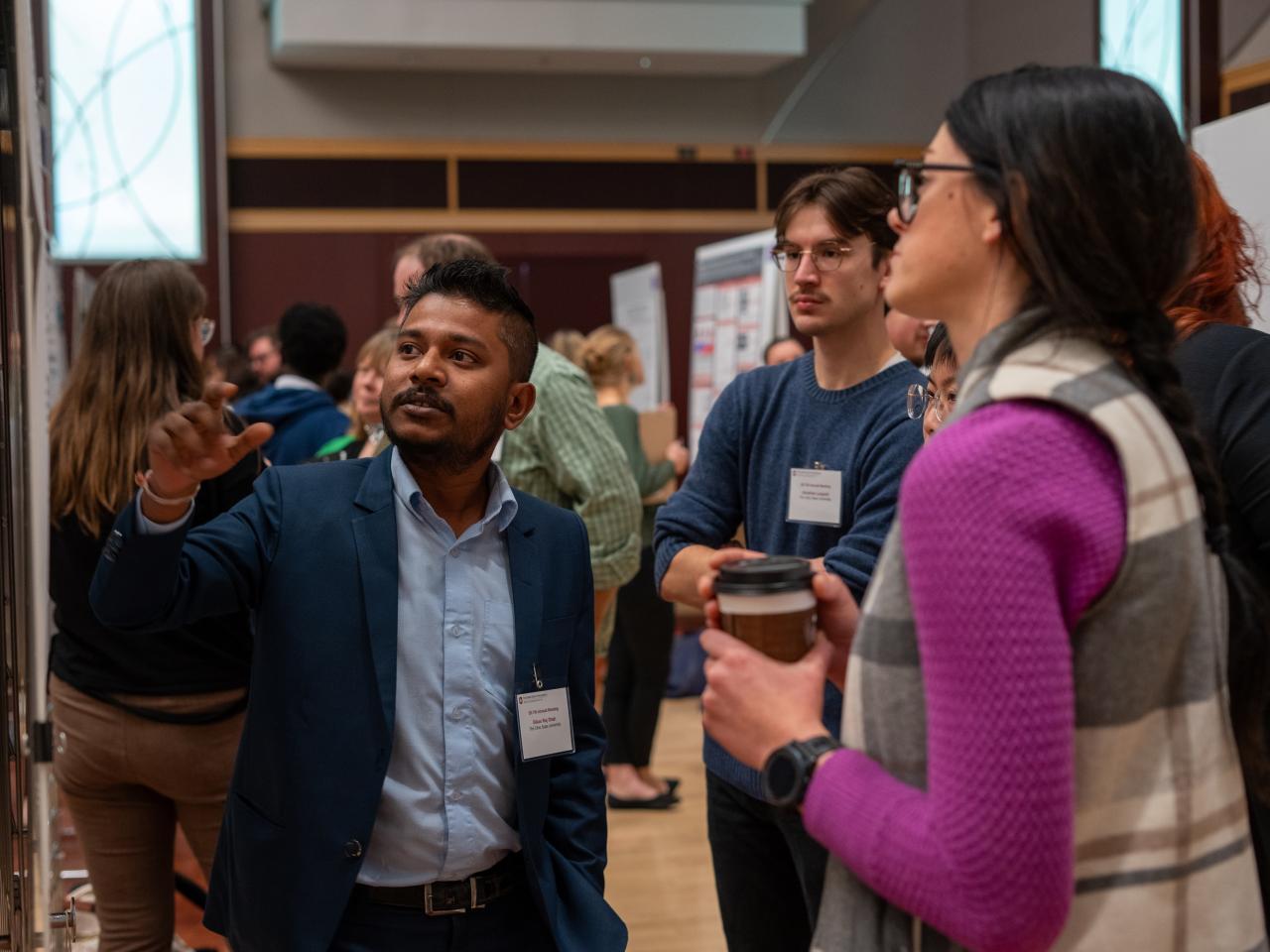 People discussing a research poster at a conference, with one person pointing at the display.