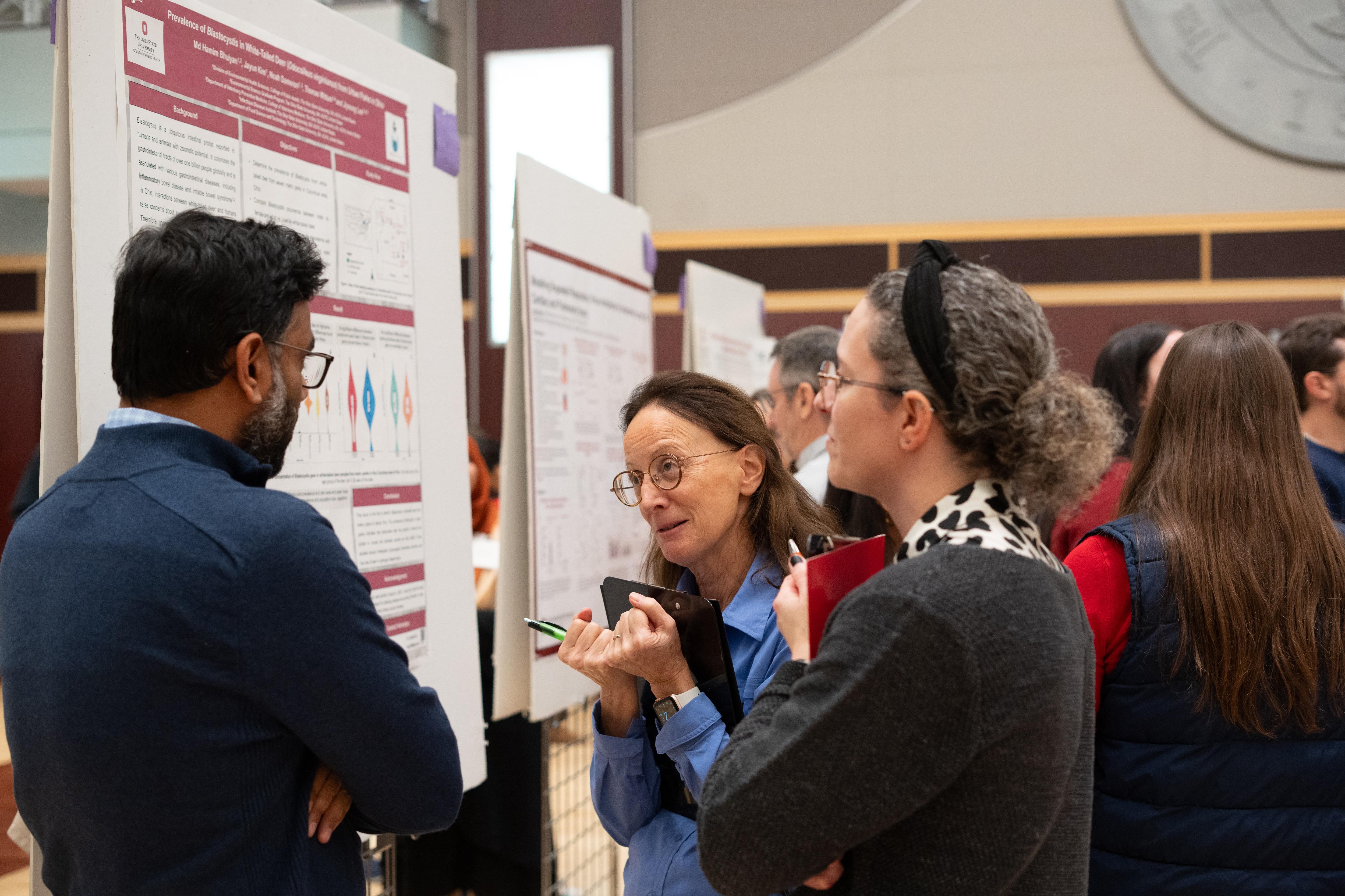 Researchers discussing a scientific poster during a conference poster session.