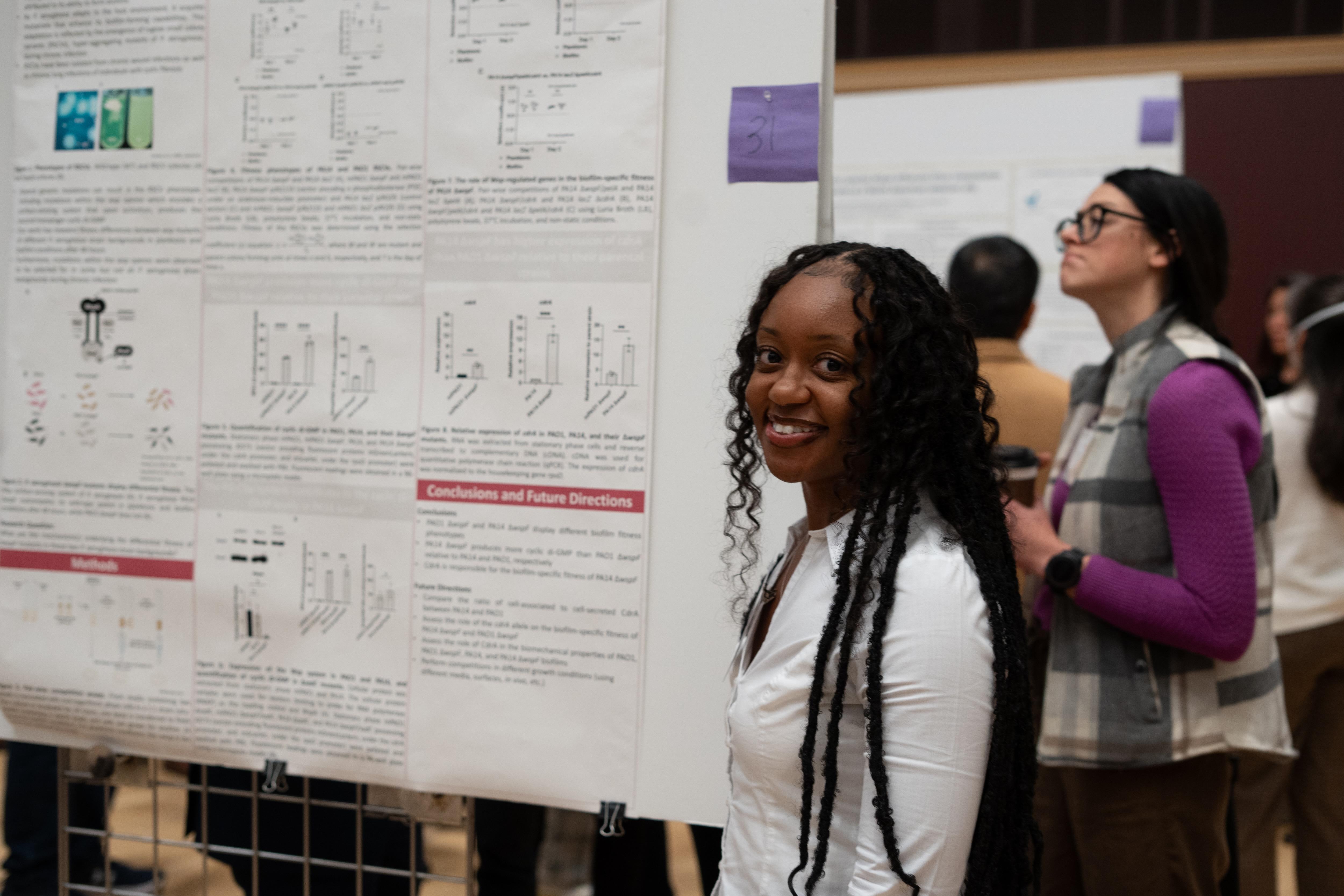 Researcher standing by a scientific poster during a conference poster session.