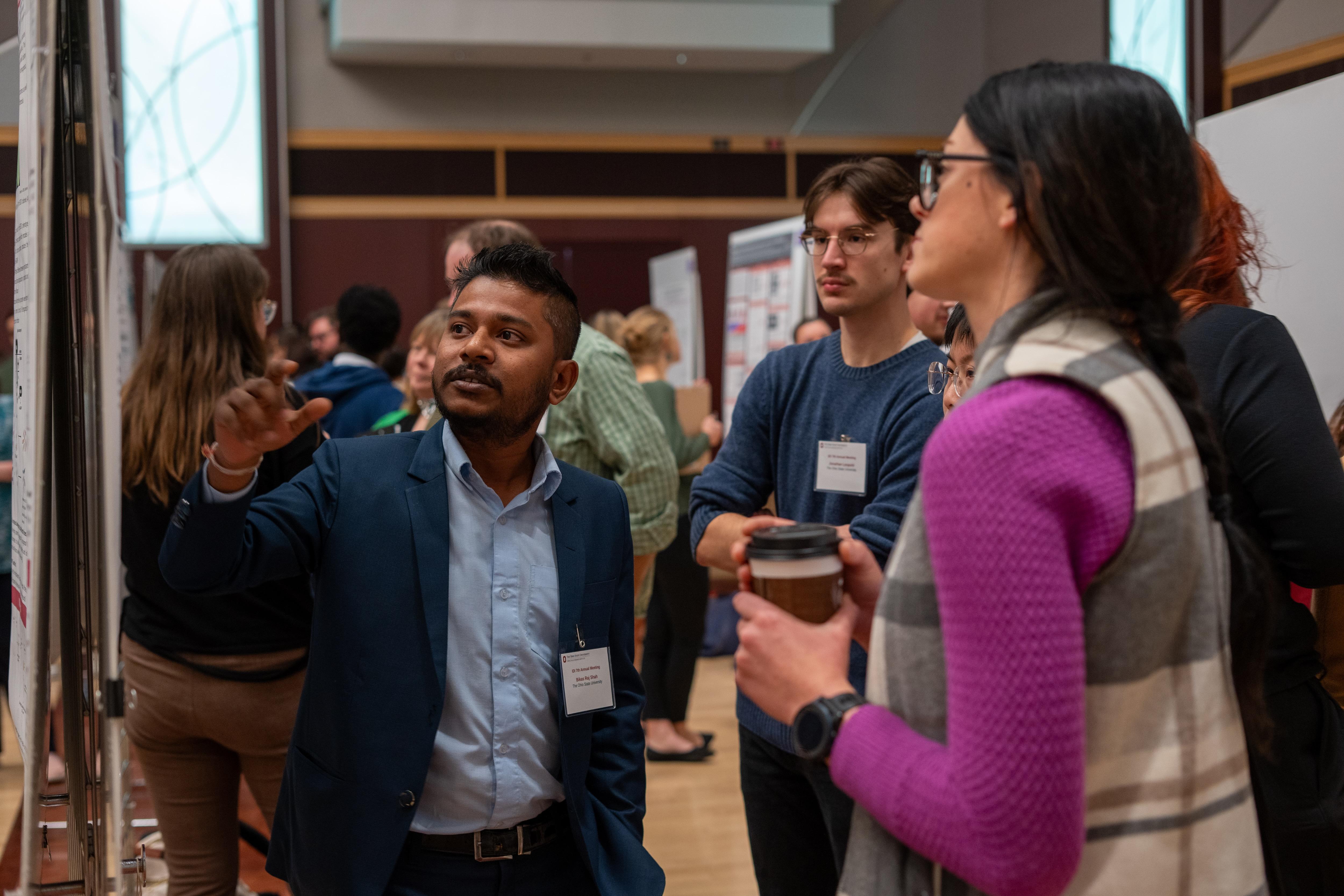 People discussing a research poster at a conference, with one person pointing at the display.