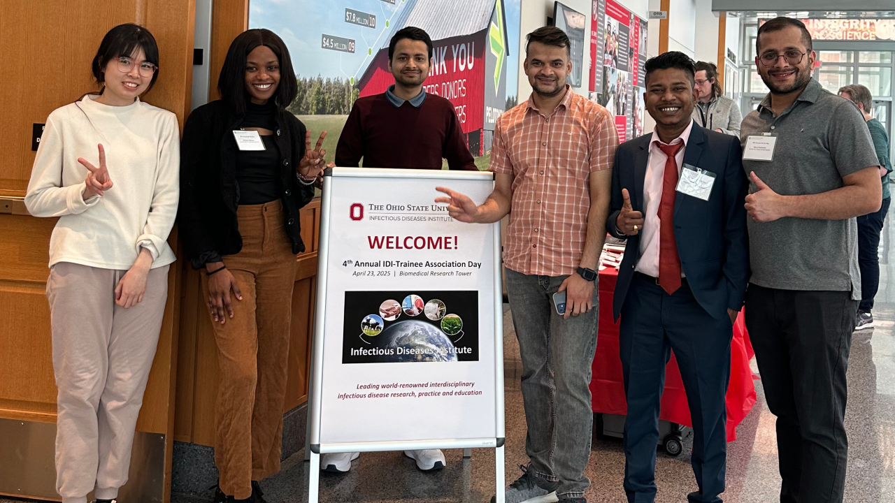 Six individuals stand around a large welcome sign for the 4th Annual IDI Trainee Association Day at The Ohio State University’s Infectious Diseases Institute, held on April 24, 2023, at the Biomedical Research Tower.